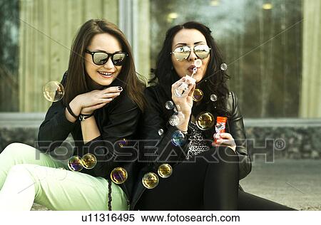 Two young woman having fun blowing bubbles View Large Photo Image Stock Photography - Two young woman having fun blowing bubbles. Fotosearch