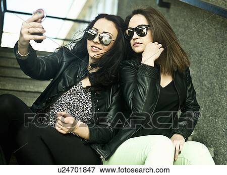 Two young woman making self portrait on mobile phone View Large Photo Image Stock Photo - Two young woman making self portrait on mobile phone. Fotosearch