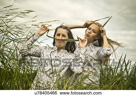 Two young women making faces with grass View Large Photo Image Stock Photograph - Two young women making faces with grass. Fotosearch