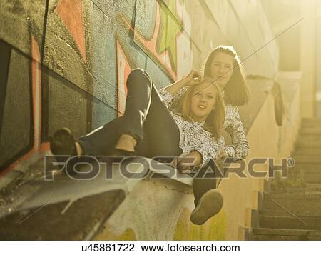 Stock Image - Two young women reclining on stairway. Fotosearch