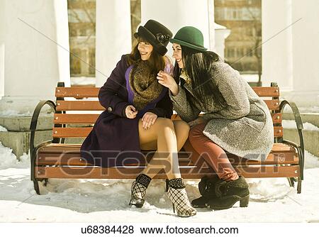 Two young women sitting on park bench in snow View Large Photo Image Stock Photo - Two young women sitting on park bench in snow. Fotosearch