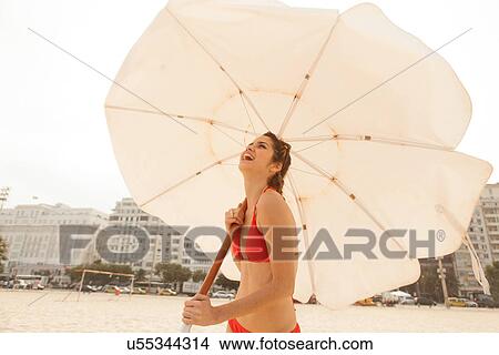 Picture - Woman in red bikini holding beach umbrella, Copacabana Beach, Rio De Janeiro, Brazil. Fotosearch
