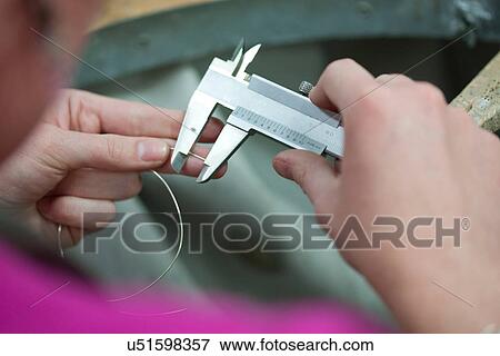Stock Photo - Woman measuring metal wire for jewelry. Fotosearch