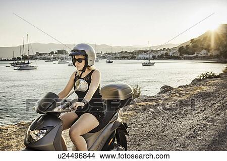 Picture - Woman riding moped along coast at Pythagorio, Samos, Greece. Fotosearch