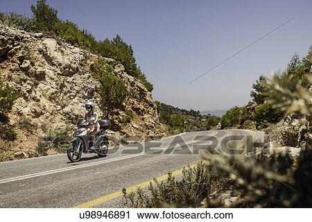 Woman riding moped along mountain road in Samos, Greece View Large Photo Image Stock Image - Woman riding moped along mountain road in Samos, Greece. Fotosearch