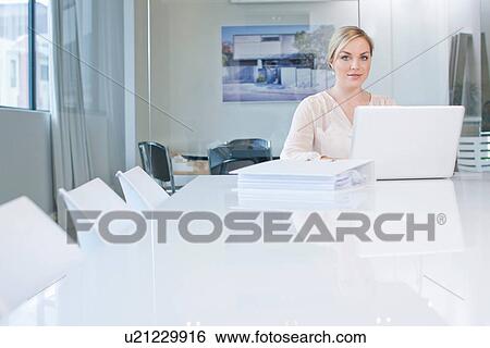Woman sitting at conference room table using laptop View Large Photo Image Stock Photograph - Woman sitting at conference room table using laptop. Fotosearch