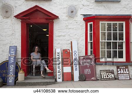 Stock Photo - Woman sitting in antique shop doorway. Fotosearch