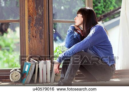 Woman sitting on windowsill View Large Photo Image Stock Photograph - Woman sitting on windowsill. Fotosearch
