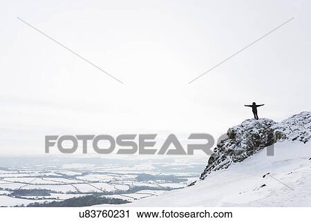 Stock Image - Woman standing on The Wrekin in winter, Shropshire, England, UK. Fotosearch