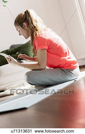 Stock Image - Woman using digital tablet on floor. Fotosearch