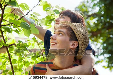 Woman with arm around man, touching leaves View Large Photo Image Stock Photo - Woman with arm around man, touching leaves. Fotosearch