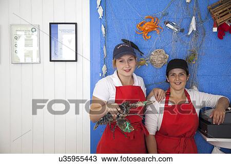Stock Image - Women holding fresh lobsters. Fotosearch