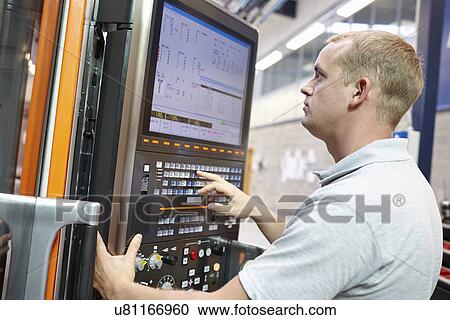 Stock Image - Worker looking at computer monitor in engineering factory. Fotosearch