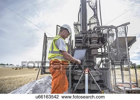 Worker using laptop to survey drilled hole made by drilling rig in field View Large Photo Image Stock Image - Worker using laptop to survey drilled hole made by drilling rig in field. Fotosearch