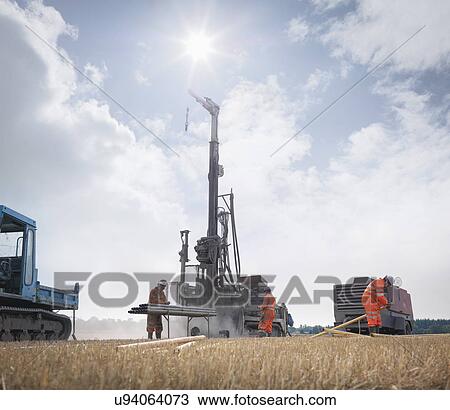 Stock Image - Workers and drilling rig exploring for coal in field. Fotosearch