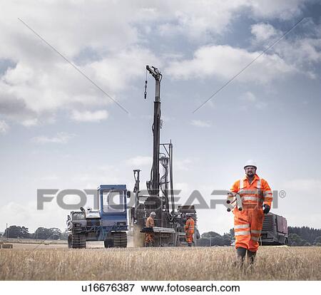 Stock Photo - Workers and drilling rig exploring for coal in field. Fotosearch