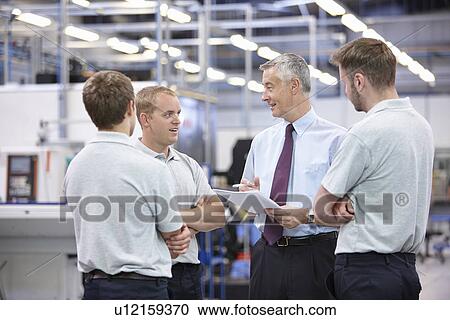 Stock Image - Workers and manager meeting in engineering warehouse. Fotosearch