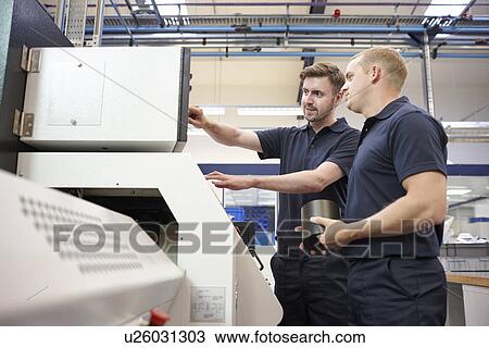 Stock Image - Workers checking looking at control panel in engineering factory. Fotosearch