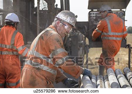Workers in hard hats operating drilling rig View Large Photo Image Stock Photograph - Workers in hard hats operating drilling rig. Fotosearch
