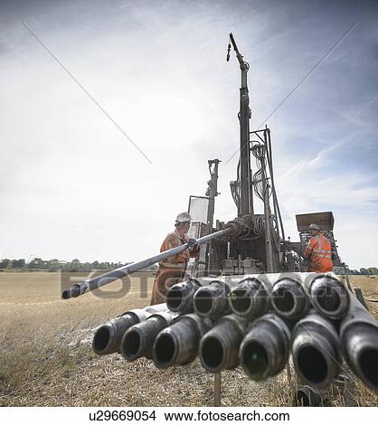 Picture - Workers operating drilling rig in field. Fotosearch