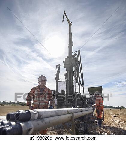 Workers operating drilling rig in field View Large Photo Image Stock Photography - Workers operating drilling rig in field. Fotosearch