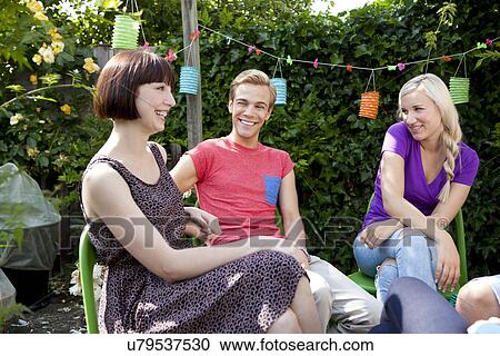 Young adult friends in garden chatting View Large Photo Image Stock Image - Young adult friends in garden chatting. Fotosearch
