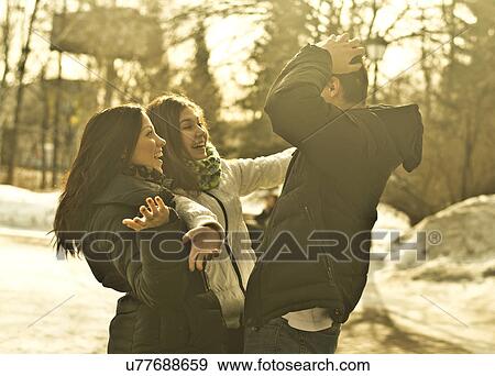 Stock Photo - Young adult friends meeting in park in winter. Fotosearch