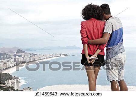 Stock Image - Young couple enjoying view from Casa Alto Vidigal, Rio De Janeiro, Brazil. Fotosearch