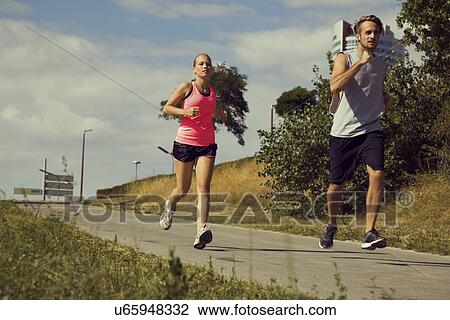 Young couple jogging down urban path View Large Photo Image Stock Image - Young couple jogging down urban path. Fotosearch