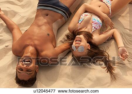 Stock Photo - Young couple lying on beach. Fotosearch