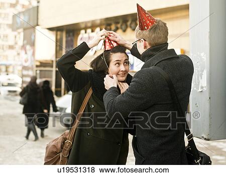 Young couple on city street adjusting party hats View Large Photo Image Stock Photo - Young couple on city street adjusting party hats. Fotosearch