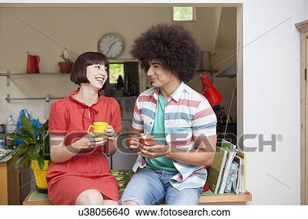 Young couple sharing a coffee in kitchen View Large Photo Image Stock Image - Young couple sharing a coffee in kitchen. Fotosearch