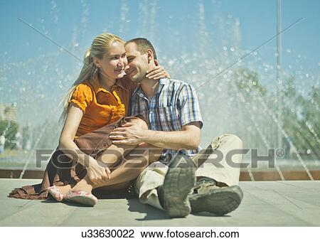 Young couple sitting next to city fountain View Large Photo Image Stock Image - Young couple sitting next to city fountain. Fotosearch