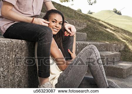 Stock Photo - Young couple sitting on steps in park. Fotosearch