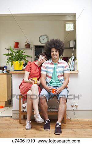 Stock Photo - Young couple sitting together in kitchen. Fotosearch
