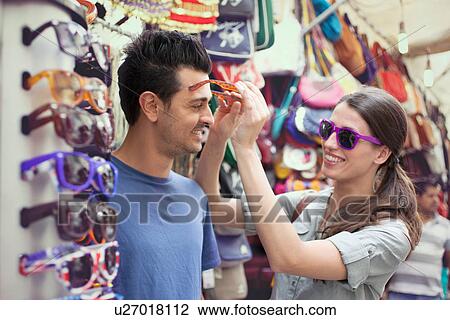 Young couple trying on sunglasses, San Lorenzo market, Florence, Tuscany, Italy View Large Photo Image Stock Image - Young couple trying on sunglasses, San Lorenzo market, Florence, Tuscany, Italy. Fotosearch