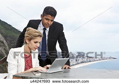 Stock Image - Young couple using laptop, Casa Alto Vidigal, Rio De Janeiro, Brazil. Fotosearch