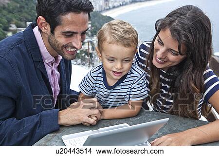 Young family looking at laptop, Casa Alto Vidigal, Rio De Janeiro, Brazil View Large Photo Image Picture - Young family looking at laptop, Casa Alto Vidigal, Rio De Janeiro, Brazil. Fotosearch