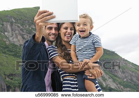 Stock Photography - Young family taking self portrait, Casa Alto Vidigal, Rio De Janeiro, Brazil. Fotosearch
