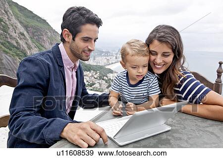 Stock Photo - Young family with laptop, Casa Alto Vidigal, Rio De Janeiro, Brazil. Fotosearch