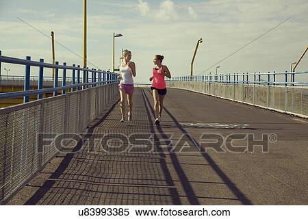 Young female joggers running on bridge View Large Photo Image Stock Photography - Young female joggers running on bridge. Fotosearch