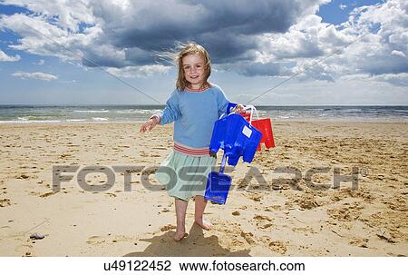 Young girl holding bucket and spade on beach, Walberswick, Suffolk, England, UK View Large Photo Image Stock Image - Young girl holding bucket and spade on beach, Walberswick, Suffolk, England, UK. Fotosearch