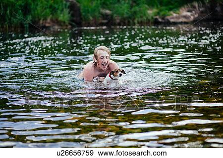 Young man and his dog playing in river View Large Photo Image Stock Photo - Young man and his dog playing in river. Fotosearch