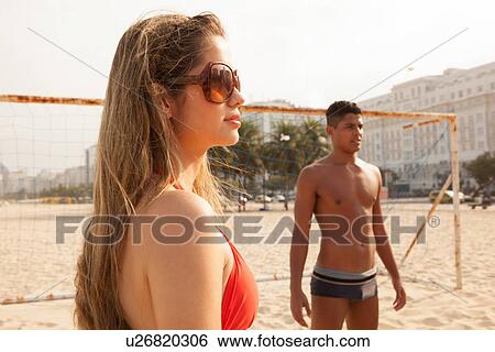 Stock Photograph - Young man and woman about to play ball on beach. Fotosearch