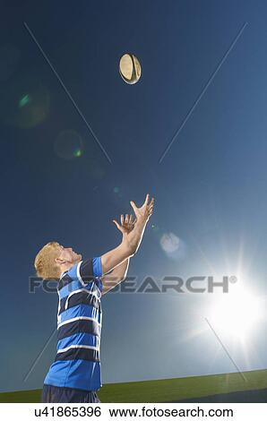 Stock Photograph - Young man catching rugby ball. Fotosearch