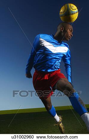 Stock Image - Young man heading football. Fotosearch