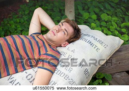 Young man lying on sack daydreaming View Large Photo Image Stock Photography - Young man lying on sack daydreaming. Fotosearch
