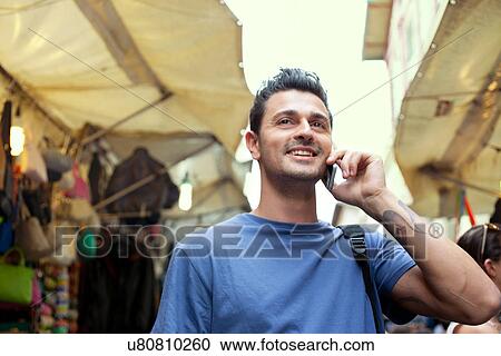Young man on cell phone, San Lorenzo market, Florence, Tuscany, Italy View Large Photo Image Stock Image - Young man on cell phone, San Lorenzo market, Florence, Tuscany, Italy. Fotosearch