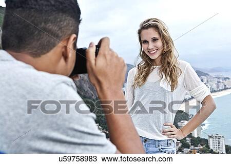 Stock Image - Young man photographing girlfriend, Casa Alto Vidigal, Rio De Janeiro, Brazil. Fotosearch