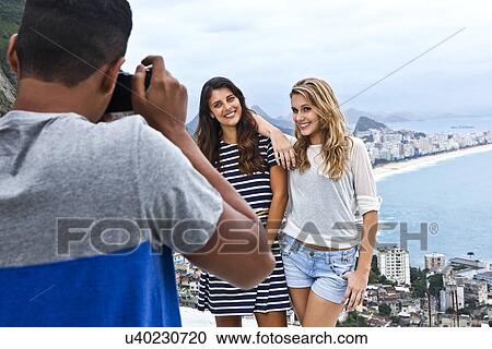 Young man photographing young women, Casa Alto Vidigal, Rio De Janeiro, Brazil View Large Photo Image Stock Image - Young man photographing young women, Casa Alto Vidigal, Rio De Janeiro, Brazil. Fotosearch